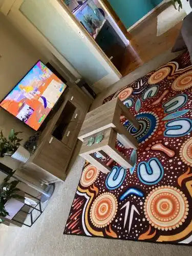 Living room with a colorful patterned rug, television, and furniture.