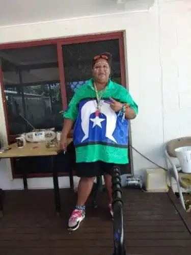 Person wearing a green and blue flag-patterned garment with a star, standing indoors.