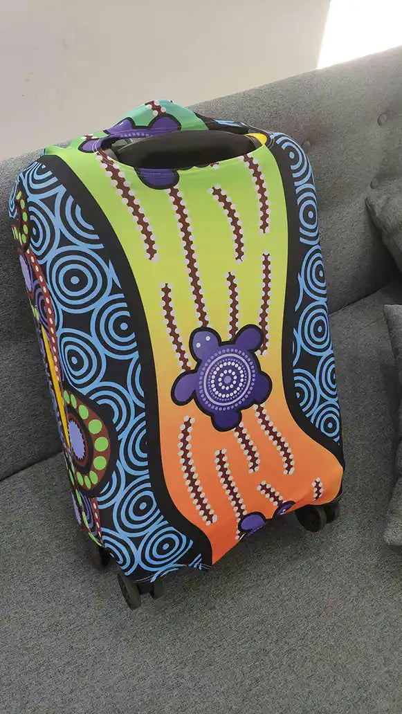 Colorful suitcase cover with abstract patterns on a gray couch.