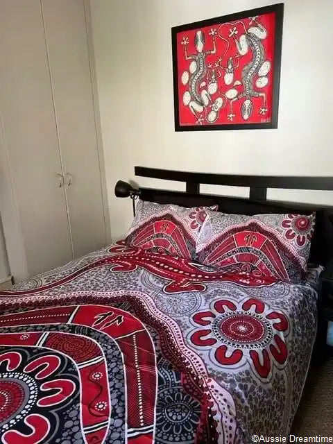 Bed with red and white patterned bedding, framed artwork above the bed.