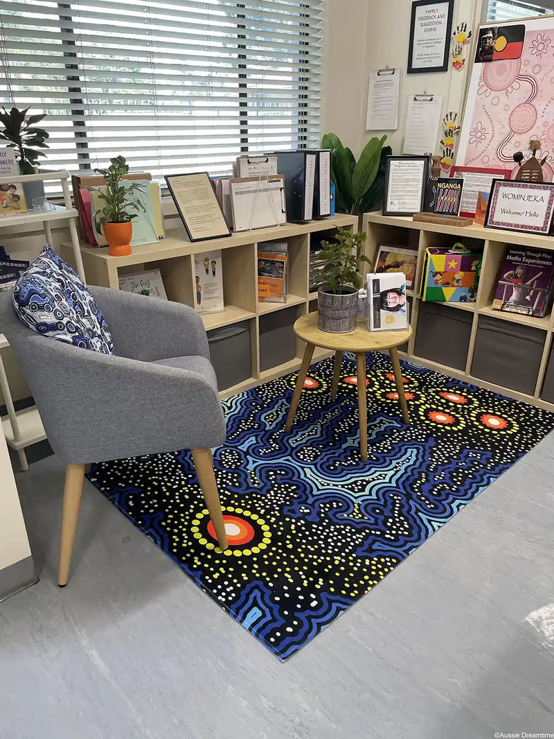 Colorful abstract rug on a gray floor with a bookshelf and chair in the background