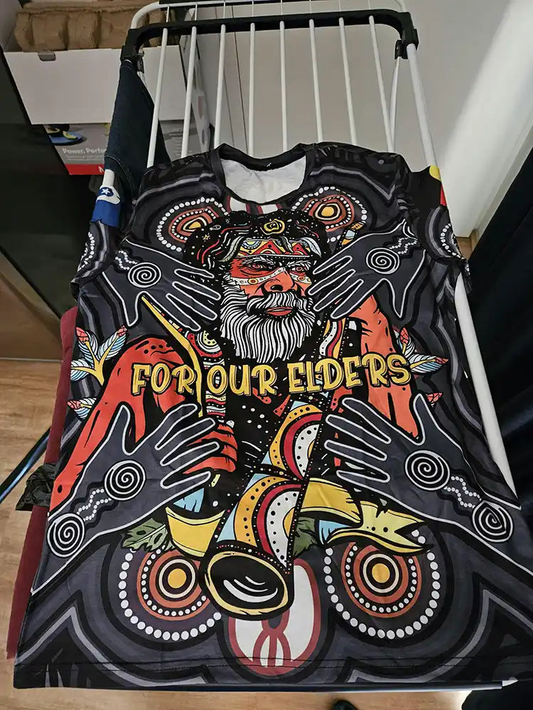 Colorful tank top with Aboriginal design and 'For Our Elders' text on a hanger.