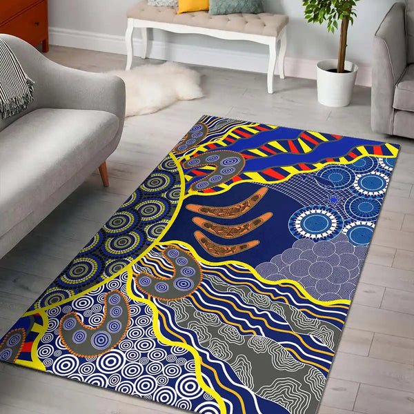 Colorful patterned rug on a wooden floor with furniture in the background. Aussie Dreamtime Aboriginal Area Rug - Beautiful Dot Art Concept With Boomerangs 1
