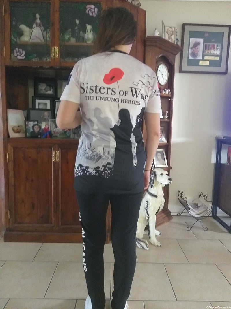 Person wearing a 'Sisters of War' t-shirt with a dog in a living room.