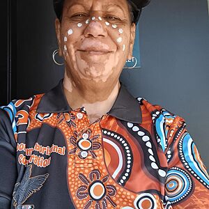 Person wearing a patterned shirt with Aboriginal art design