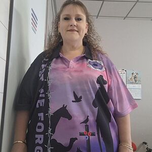 Person wearing a pink and purple shirt with graphic designs in an indoor setting