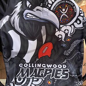Collingwood Magpies sports jersey with Indigenous design elements on a brick wall background