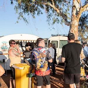 Group of people at a campsite with RVs and trees in the background