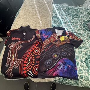 Two patterned shirts on a textured surface with a colorful fabric background.