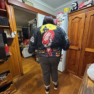 Person wearing a colorful jacket with a cartoon character design in a room.