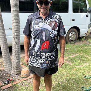 Man wearing a colorful polo shirt with a graphic design, standing outdoors.
