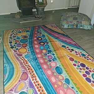 Colorful polka dot rug on a wooden floor with a television and pet bed in the background.