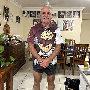 Man standing in a living room with a casual pose, wearing a sports jersey.