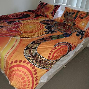 Bedspread with orange and brown patterns on a bed in a room.