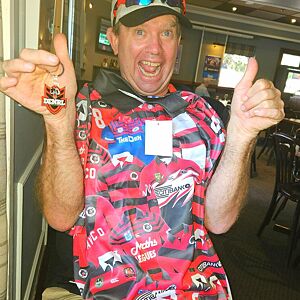 Person wearing a colorful shirt with various logos and giving a thumbs-up gesture.